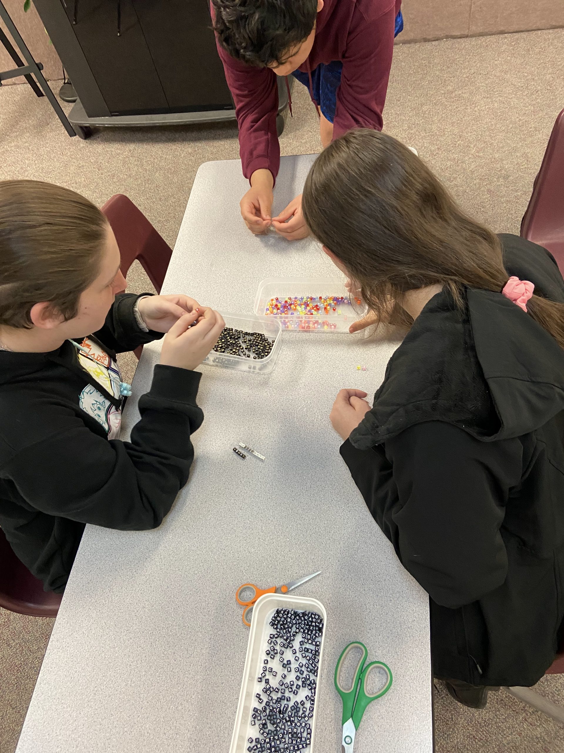 3 students looking at beads at a table