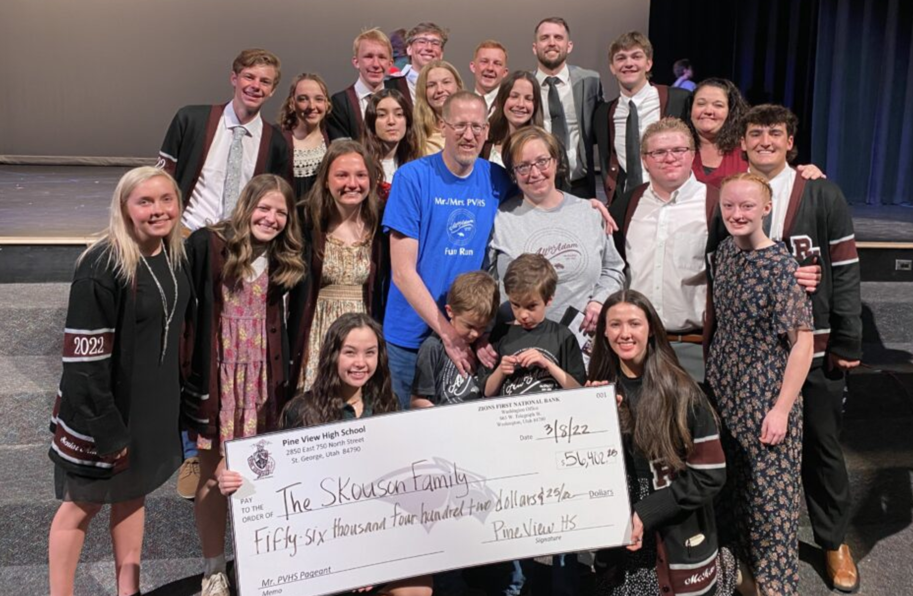students and adults holding a check